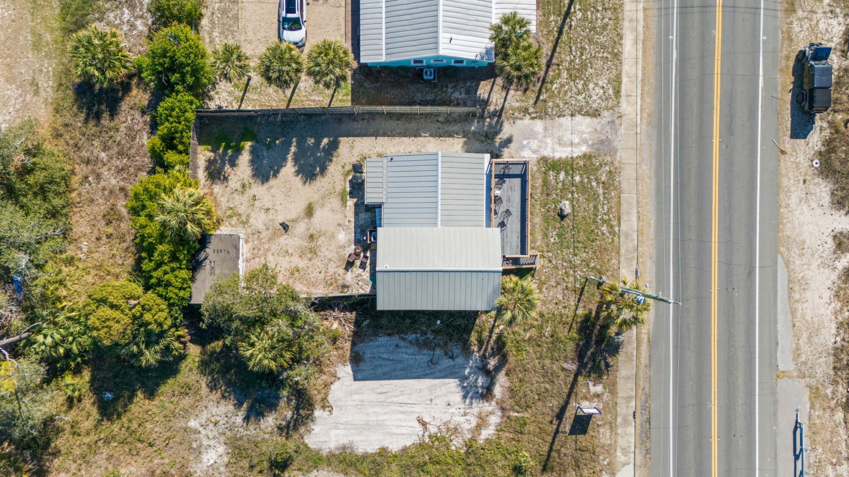 An aerial view of a property with a large building, a paved driveway, and a road nearby.