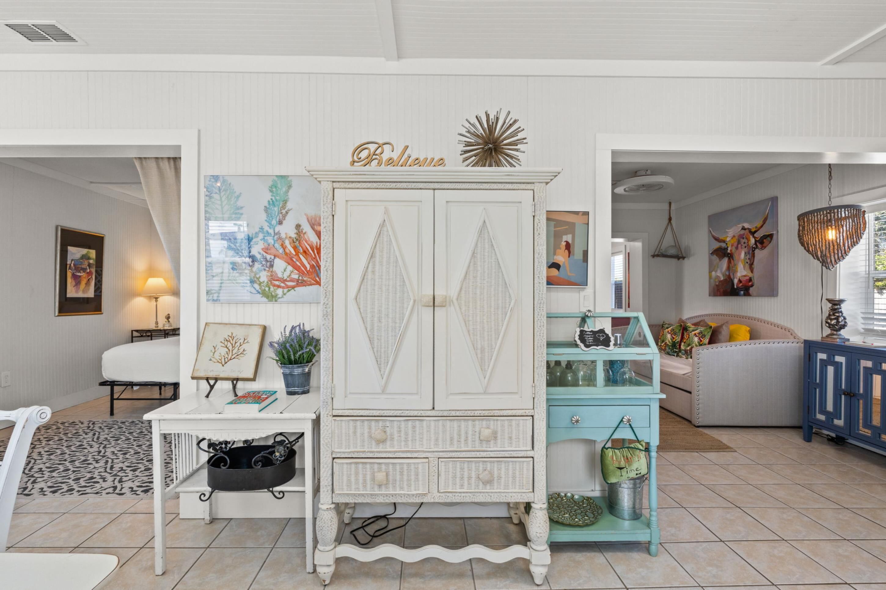 A living room with a white cabinet, a teal sideboard, and a sofa.