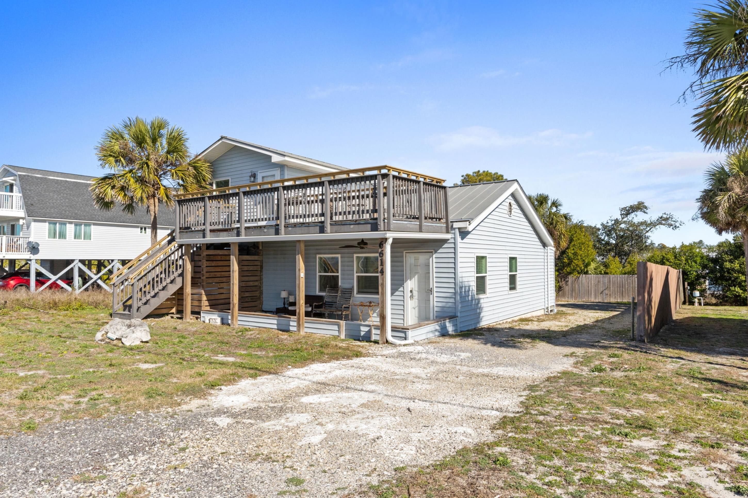 A two-story house with a balcony, a covered porch, and a gravel driveway.