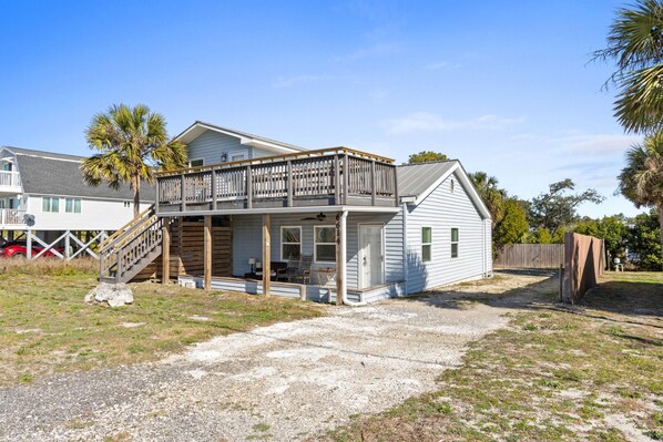 A two-story house with a balcony, a covered porch, and a gravel driveway.