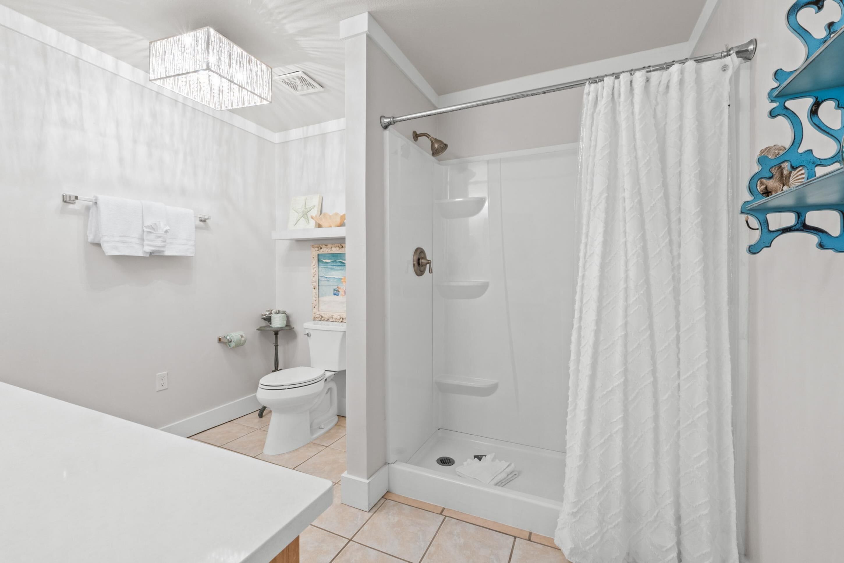A modern bathroom with a shower, toilet, and sink.