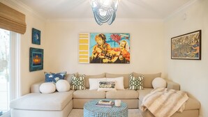 A living room with a beige sectional sofa, a round coffee table, and artwork on the walls. - 2BR/2.5BA in the PERFECT location in Ocean Springs! Downtown Sanctuary (Ocean Springs)