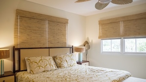A bedroom with a large bed, two bedside tables, a lamp, and a window with blinds. - 2BR/2.5BA in the PERFECT location in Ocean Springs! Downtown Sanctuary (Ocean Springs)