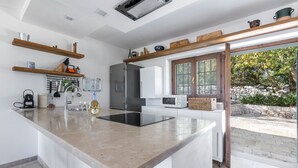 A modern kitchen with a central island, stainless steel appliances, and wooden shelves.