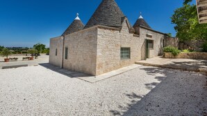 A stone building with three conical roofs and a gravel driveway.