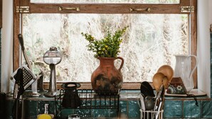 A kitchen with a rustic wooden window frame, a potted plant, and various kitchen utensils. - Country house in the middle of nature. (Chinchero)