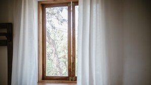 A bedroom with a large window, white curtains, and a wooden headboard. - Country house in the middle of nature. (Chinchero)