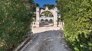 Un sendero de grava que conduce a un edificio blanco con un arco de piedra.