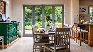 Una cocina moderna con comedor, grandes puertas correderas de vidrio que dan a un jardín y un tragaluz sobre la mesa.
