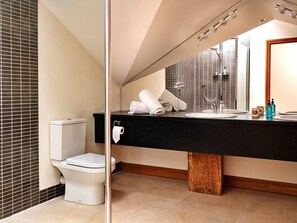 A modern bathroom with a black countertop, white toilet, and a wooden vanity. - The Loft (Kingham)