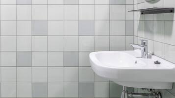 Ein Badezimmer mit einem weißen Waschbecken, einem Spiegel und einem Handtuchhalter.