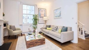 A living room with a sofa, armchair, coffee table, and a staircase. - The Chelsea Classic - Splendid 3bdr House With Terrace (London)