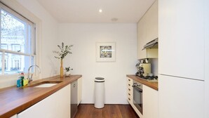 A compact kitchen with a wooden countertop, a sink, a stove, and a trash bin. - The Chelsea Classic - Splendid 3bdr House With Terrace (London)