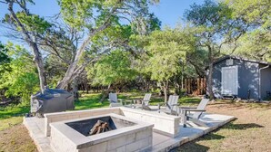 A backyard with a stone fire pit, outdoor seating, and a shed.