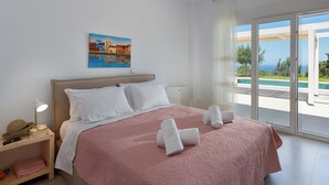 A hotel room with a bed, a nightstand, a painting, and a view of the sea.