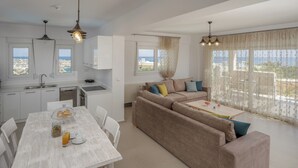 A modern living space with a kitchen, dining area, and a sofa set. - Blue Hills Villas by Estia, Green 3 (Ammoudi)