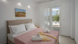 A bedroom with a bed, pillows, a blanket, and a painting on the wall. - Blue Hills Villas by Estia, Green 3 (Ammoudi)