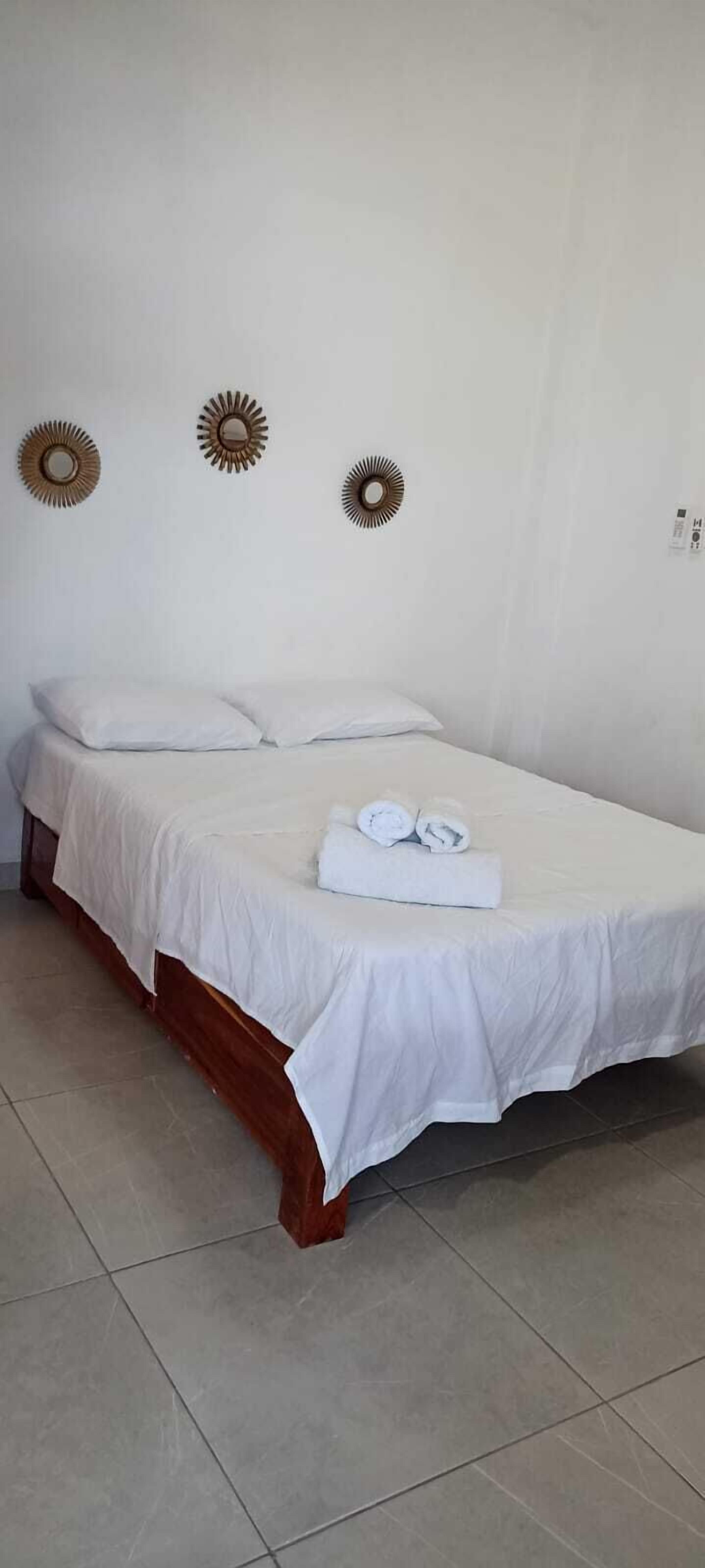 A single bed with white bedding and two decorative wall mirrors.
