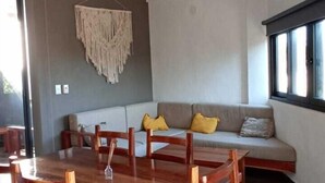 A dining area with a wooden table and chairs, a ceiling fan, and a sofa with cushions. - Edificios Regam (El Cuyo)