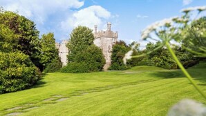 Un castillo rodeado de abundante vegetación y un cielo despejado.