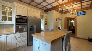 Una cocina moderna con armarios blancos, electrodomésticos de acero inoxidable, una isla de madera y una lámpara de araña.