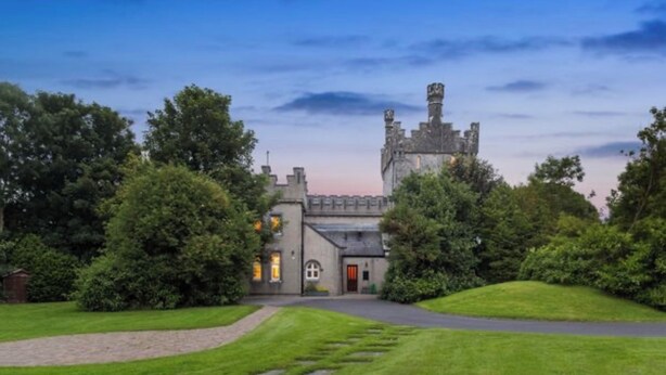 Un edificio con aspecto de castillo, un camino empedrado y amplios jardines verdes.