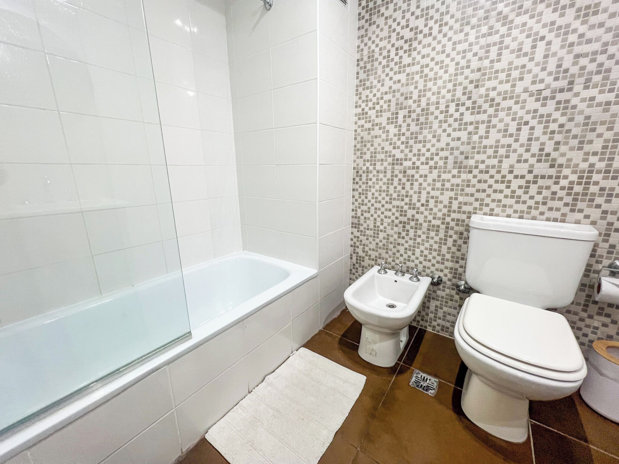 A bathroom with a white bathtub, a bidet, and a toilet.