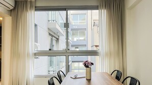 Un comedor moderno con una mesa de madera, sillas negras y un jarrón con flores.