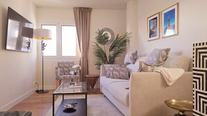 Un salon avec un canapé, des fauteuils, une table basse, une lampe et une plante en pot.