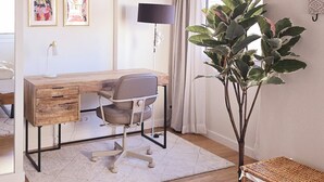 Une chambre à coucher moderne avec un bureau en bois, une chaise, une grande plante et un panier en osier.