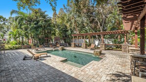 A pool area with a pergola, lounge chairs, and a barbecue setup. - Spacious 4BR pool home, billiards, BBQ, large patio, pool and pool deck (Tampa)