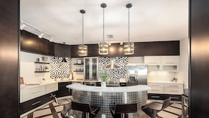 A modern kitchen with a central island, bar stools, and pendant lighting. - Spacious 4BR pool home, billiards, BBQ, large patio, pool and pool deck (Tampa)