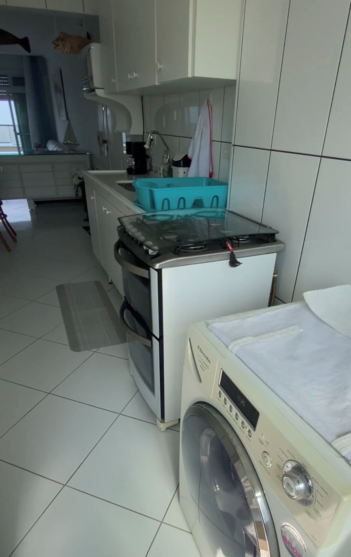 Une cuisine de taille réduite équipée d’un lave-linge, d’une cuisinière et d’un évier.