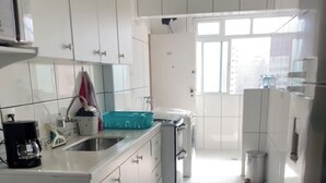 Uma cozinha moderna com armários brancos, uma pia de aço inoxidável e um forno embutido.