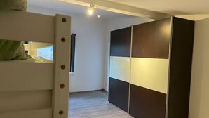 A room with a bunk bed, a wardrobe with a sliding door, and a window with curtains. - Apartment Ndé (Abstatt)