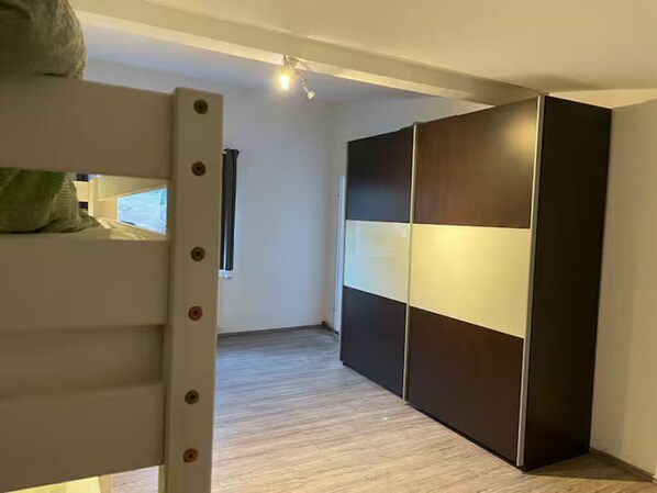 A room with a bunk bed, a wardrobe with a sliding door, and a window with curtains. - Apartment Ndé (Abstatt)