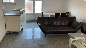 A modern living room with a leather sofa, a glass coffee table, and a dining area with a white table and chairs. - Apartment Ndé (Abstatt)