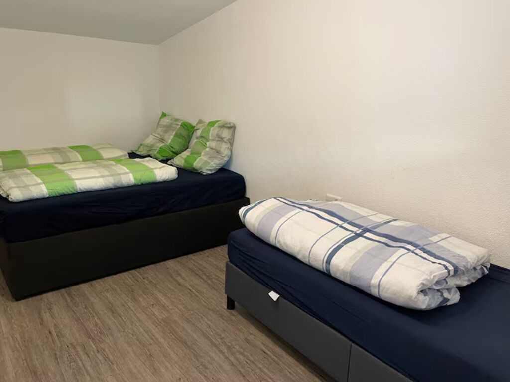 Un dormitorio pequeño con una cama individual y dos camas, cada una con un estilo de ropa de cama diferente.