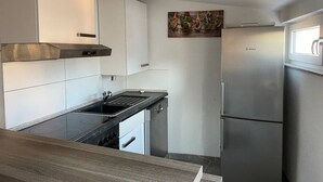 A compact kitchen with white cabinets, a Bosch refrigerator, and a wooden countertop. - Apartment Ndé (Abstatt)