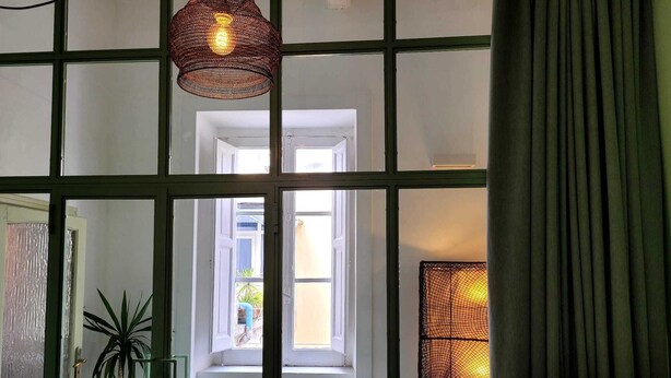 Une pièce avec une fenêtre, un luminaire suspendu et un rideau.
