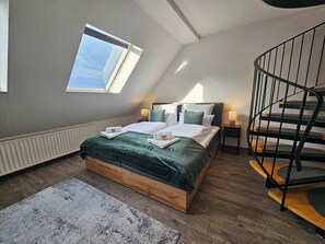 A bedroom with a skylight, a bed with green bedding, a nightstand with a lamp, and a spiral staircase. - Wohlfühlapartment - 3 Schlafzimmer - Dachterrasse (Eisenach)