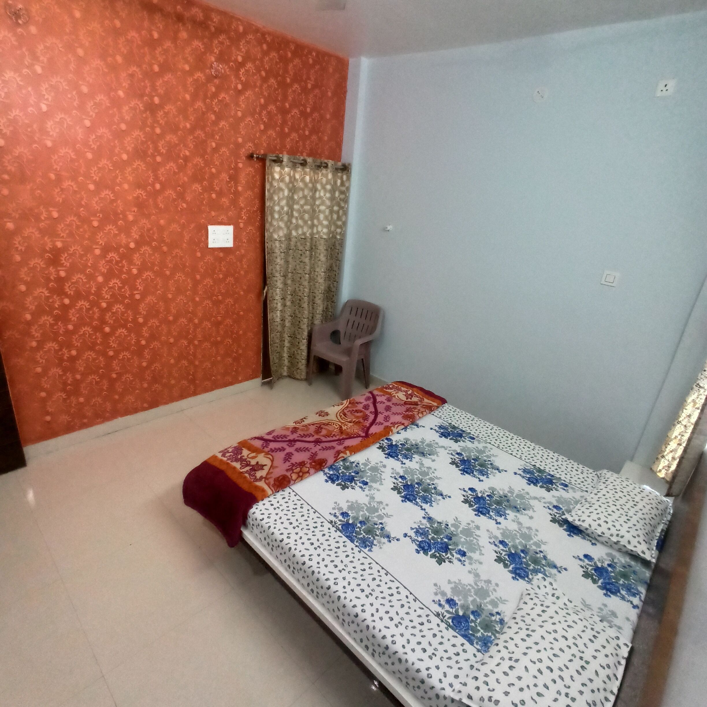 A room with a bed, a chair, and a curtain.