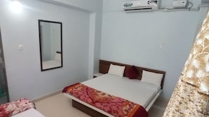Ein Hotelzimmer mit Bett, Nachttisch, Spiegel, Klimaanlage und Vorhang.