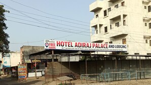 Ein Gebäude mit einem Schild für das Hotel Adiraj Palace und Lodging, das kostenlose Parkplätze und einen 24-Stunden-Service, klimatisierte Zimmer, Notstromversorgung, ein Geschenkeladen, Zimmerservice, Warmwasser und einen Mietautoverleih bietet.