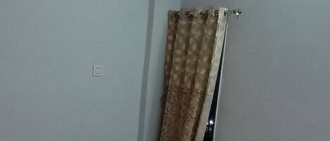 A bedroom with a bed, a curtain, and a light fixture.