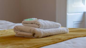 A neatly folded white towel on a yellow blanket on a bed.