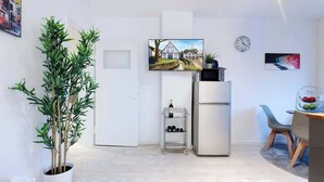 A modern kitchen with a refrigerator, a wine rack, and a dining area with a table and chairs. - MOLA Apartments-Historisches Apartment in Altstadt (Herdecke)