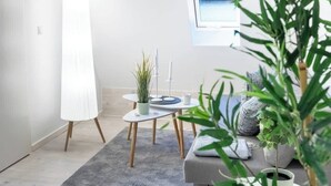 A modern living room with a large floor lamp, a round table with a plant, and a sofa with cushions. - MOLA Apartments-Historisches Apartment in Altstadt (Herdecke)