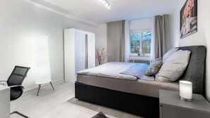 A modern bedroom with a bed, a desk, and a wardrobe. - MOLA Apartments-Historisches Apartment in Altstadt (Herdecke)