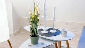 A modern, minimalist room with a white table featuring a potted plant, candles, and a small container. - MOLA Apartments-Historisches Apartment in Altstadt (Herdecke)